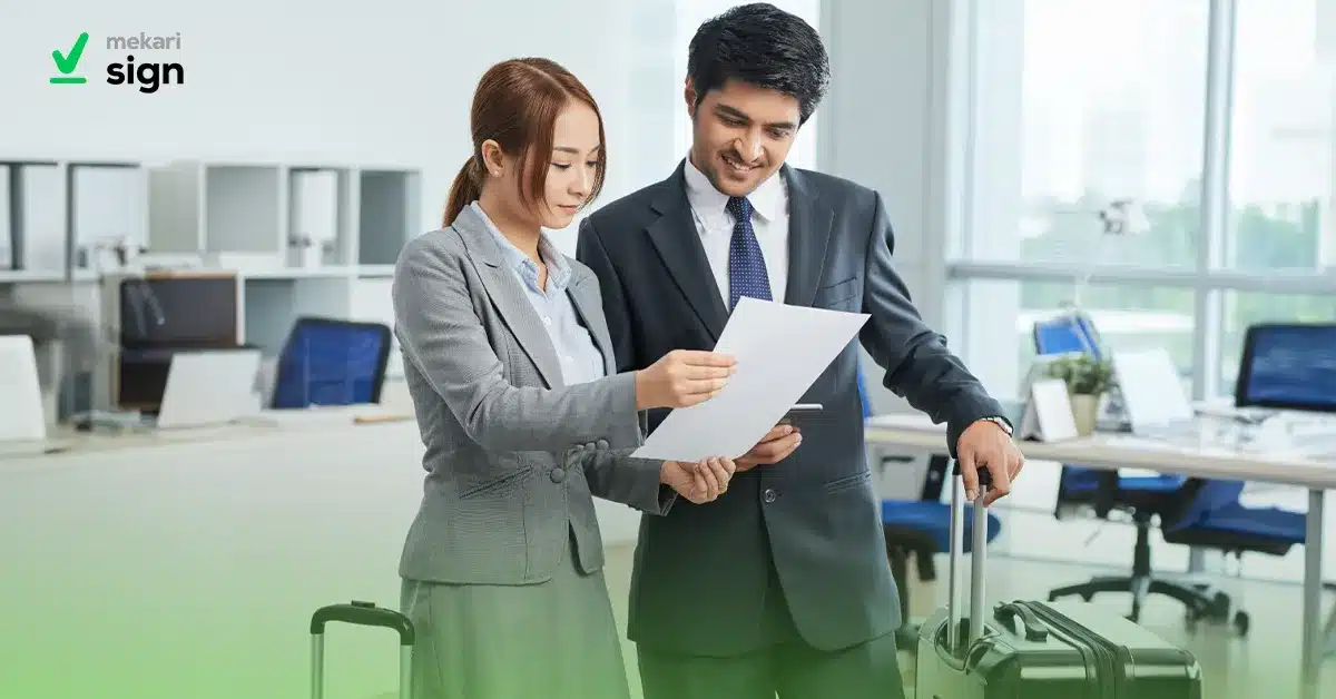 Dua karyawan profesional sedang meninjau dokumen contoh surat cuti di kantor modern, relevan untuk berbagai kebutuhan cuti kerja.